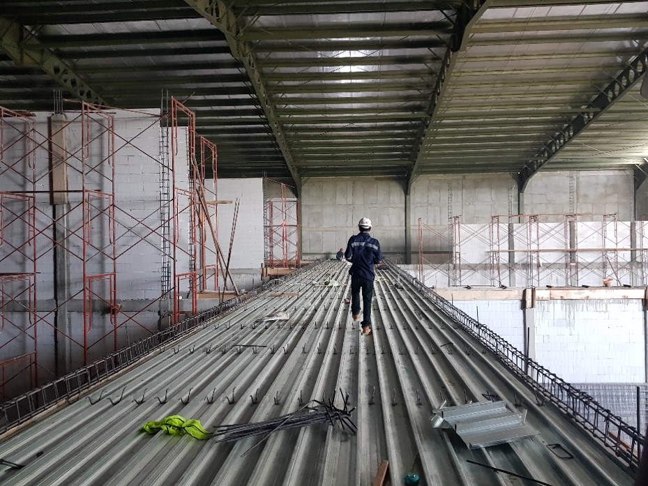 Pekerja berjalan di atas pelat lantai baja bergelombang di proyek bioskop CGV Lawu Plaza